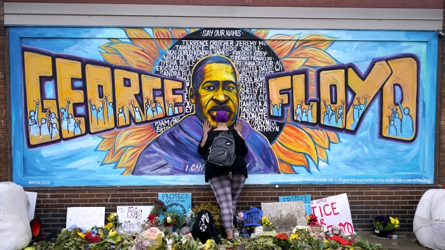 Damarra Atkins pays respect to George Floyd at a mural at George Floyd Square