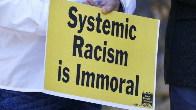 Pastor Jose Rodriquez holds a sign against systemic racism