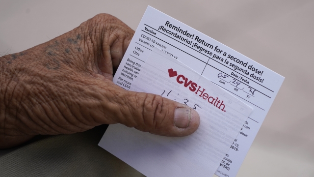 A man holds his vaccination reminder card after having received his first shot at a pop-up vaccination site
