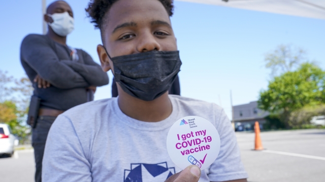 A teen poses for a photo with his vaccination sticker after being inoculated with the first dose of a COVID-19 vaccine.