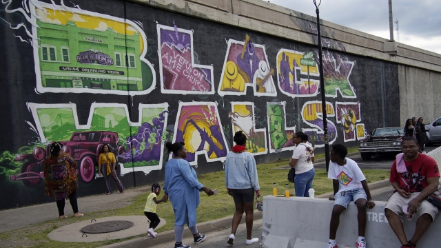 People by a "Black Wall Street" mural in the Greenwood district during centennial commemorations of the Tulsa Race Massacre