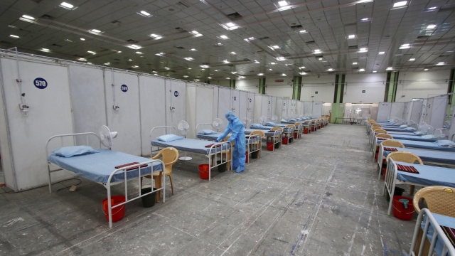 A health worker arranges beds at a temporary COVID-19 care center at the Nandambakkam Trade Center in Chennai, Tamil Nadu