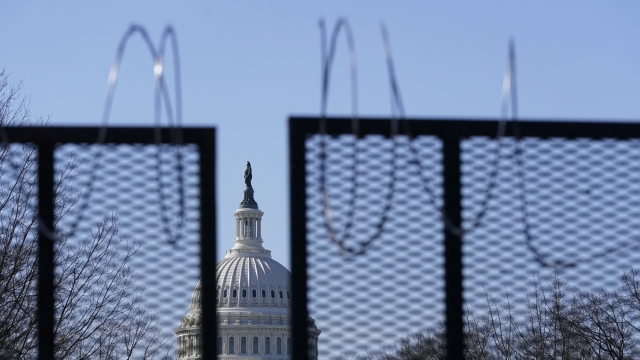 The U.S. Capitol dome stands past partially-removed razor wire hanging from a security fence