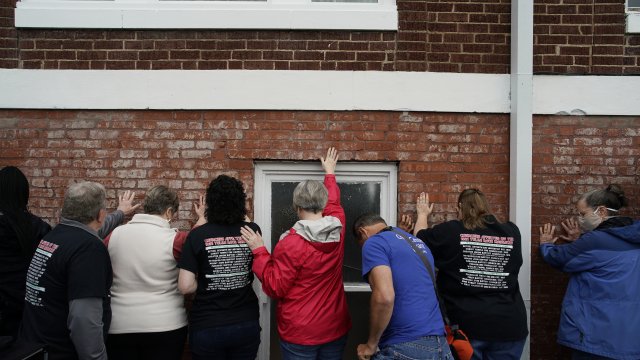 People pray as they hold their hands on a prayer wall outside of the historic Vernon African Methodist Episcopal Church