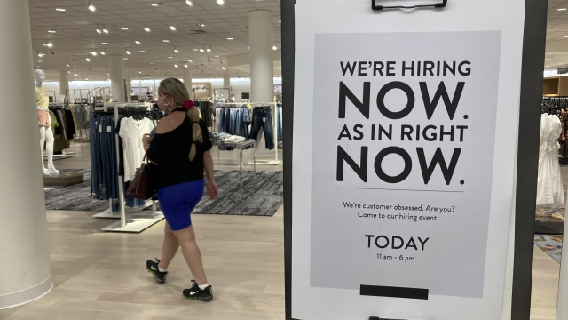 A customer walks behind a sign at a Nordstrom store seeking employees in Coral Gables, Florida