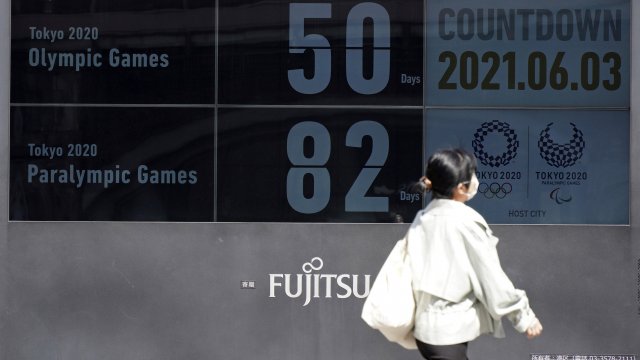 People walk past the countdown clock for the Tokyo 2020 Olympic and Paralympic Games