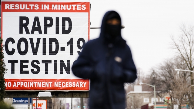 A person wearing face mask walks near a sign advertising a rapid COVID-19 testing site.