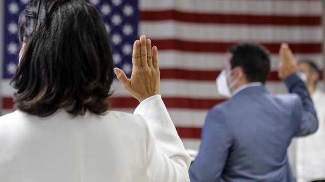 People take the oath of citizenship during a naturalization ceremony at U.S. Citizenship and Immigration Services