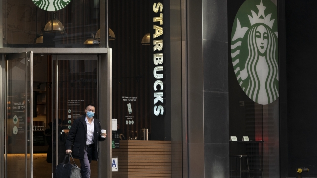 A man carries a beverage as he walks out of a Starbucks coffee shop