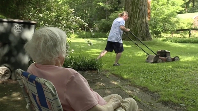 Woman watches man mow.