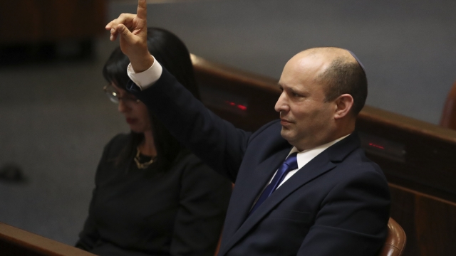 Israel's new prime minister Naftali Bennett raises his hand during a Knesset session in Jerusalem Sunday.