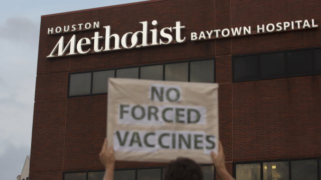 People bring signs to protest Houston Methodist Hospital system's rule of firing any employee who is not immunized.