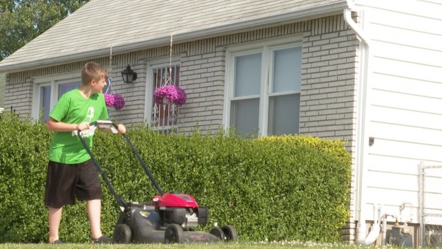 A teen mows a lawn.