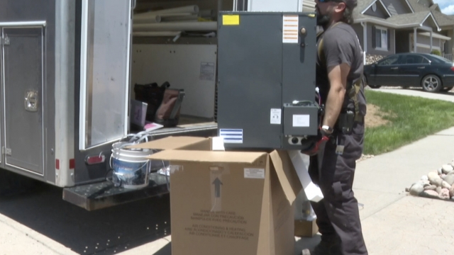 Man lifts an AC unit out of a box.