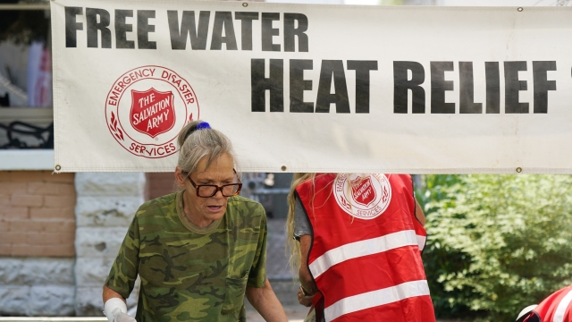 A pedestrian takes a bottle of water at a Salvation Army hydration station during a heatwave as temperatures hit 115-degrees