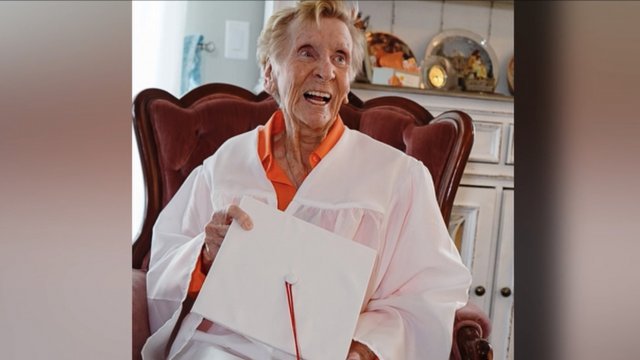 A woman holds her high school diploma.
