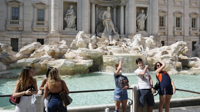 Tourists throw their coins into the Trevi fountain as a wish to come back to Rome.