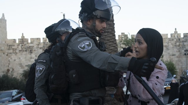 An Israeli border police officer faces off with a Palestinian woman