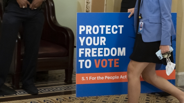 An aide carries a sign to the Senate floor as the Senate prepares for a key test vote on the For the People Act