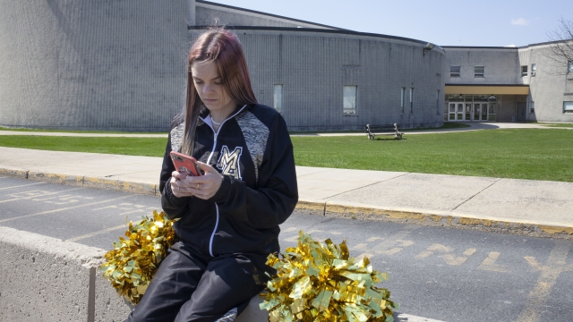Brandi Levy wears her cheerleading outfit as she looks at her phone