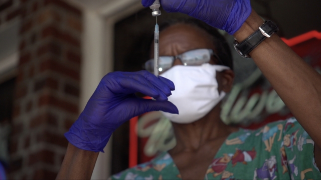 Health care worker prepares vaccine needle