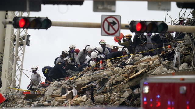 Search and rescue workers comb the rubble of an oceanfront condo building that collapsed,