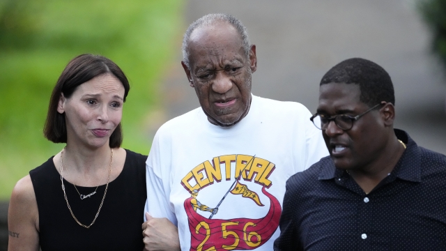 Comedian Bill Cosby, center, and spokesperson Andrew Wyatt, right, approach media gathered outside Cosby's home