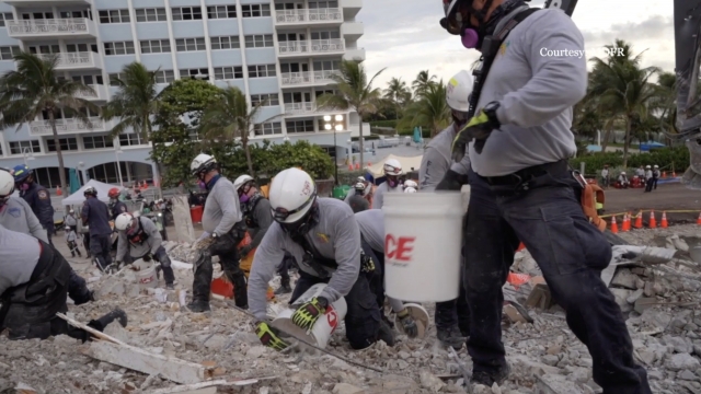 Workers dig through rubble
