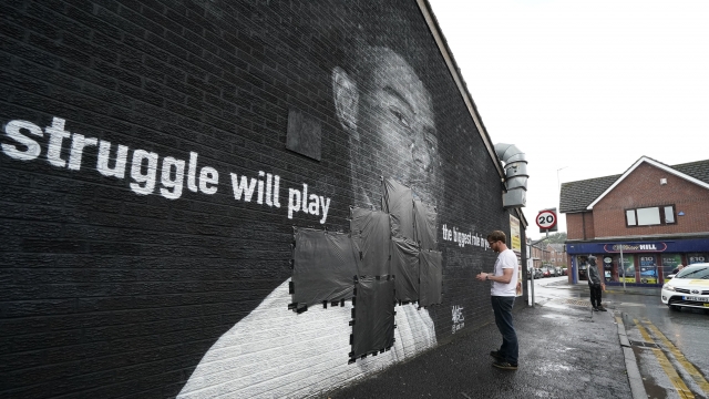 Ed Wellard, from Withington, tapes bin liners across offensive wording on the mural of Manchester United