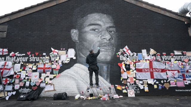 Street artist Akse P19 repairs the mural of Manchester United striker and England player Marcus Rashford