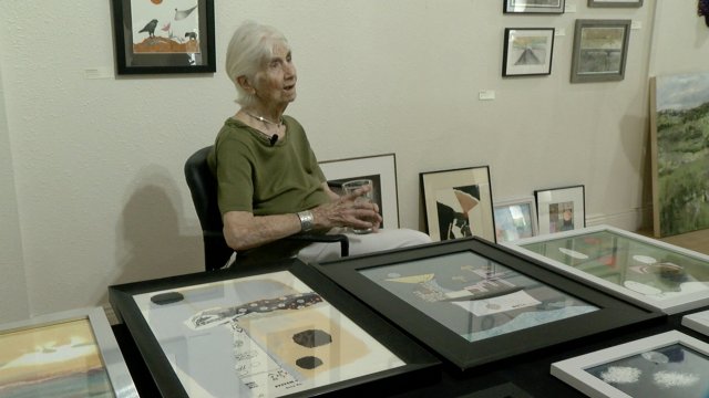 Artist sits by her work.