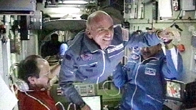 Space station commander Yury Usachev, left, welcomes California millionaire Dennis Tito, center, to the space station