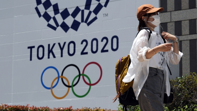 A woman wearing a mask in front of a Tokyo 2020 Summer Olympics display