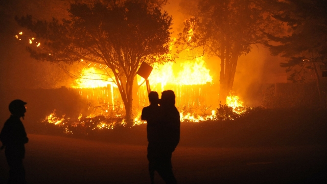 Folks watch a home burn in the hills above Santa Barbara, California