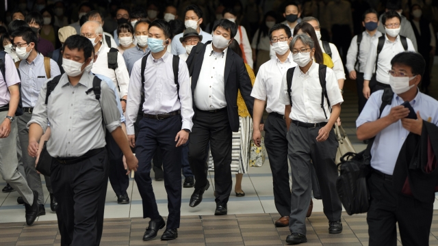 commuters wearing face masks walk in a passageway