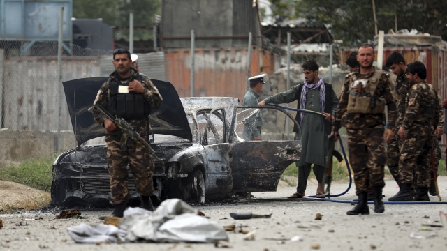 Afghan security personnel inspect a damaged vehicle which was firing rockets in Kabul.