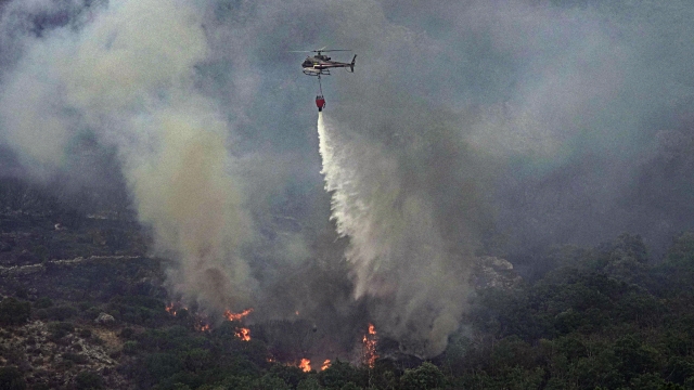 A helicopter drops water to put out flames on the island of Sardinia, Italy.