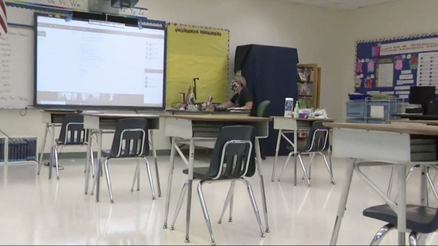 Teacher sits in an empty classroom.