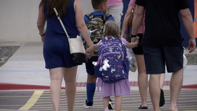 Girl walks to school with parents.