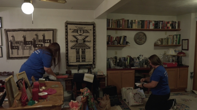 Women pack items in a house.