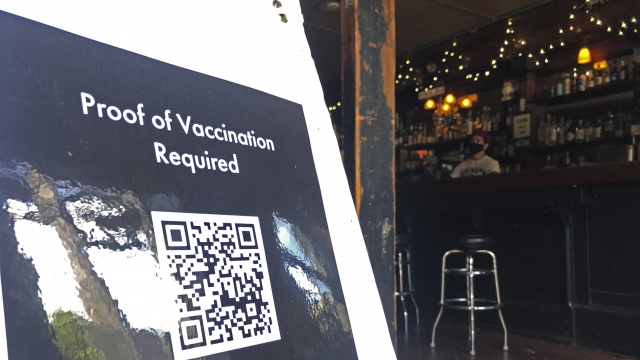 A proof of vaccination sign is posted at a bar in San Francisco.