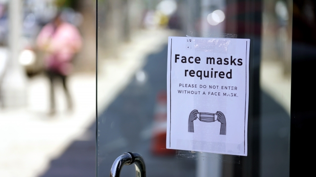 A sign outside of a store advises shoppers to wear masks.