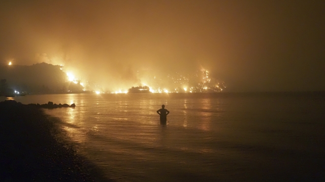 A man watches as wildfires approach Kochyli beach near Limni village on the island of Evia