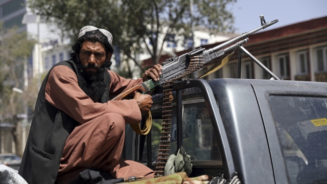 A Taliban fighter sits on the back of a vehicle with a machine gun in Kabul, Afghanistan.