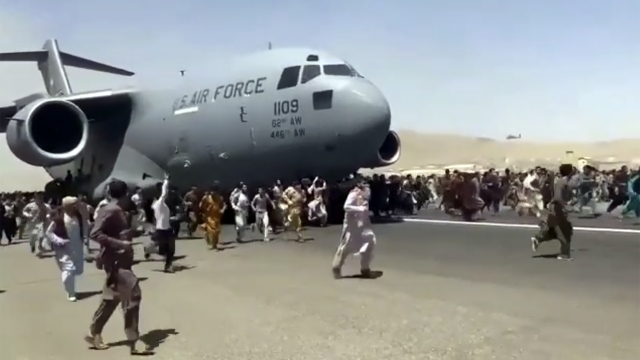 Hundreds of people run alongside a U.S. Air Force C-17 transport plane at the international airport in Kabul, Afghanistan