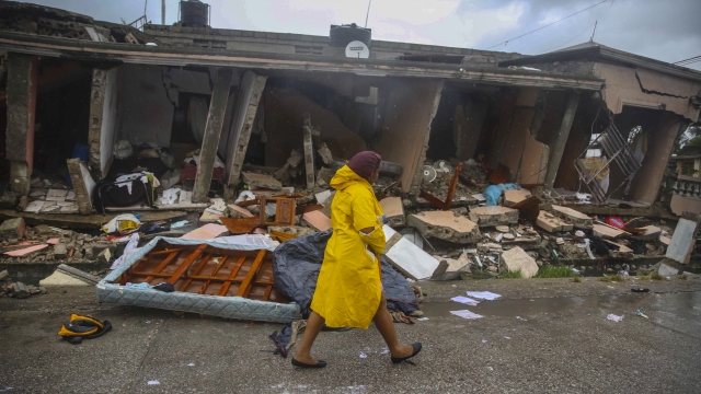 A woman walks in the rain past earthquake-destroyed homes the day after Tropical Storm Grace swept over Les Cayes, Haiti