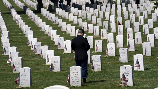 A military service member pauses over the graves of the fallen soldiers.