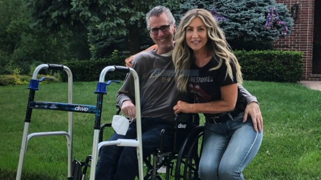 Man sits in a wheelchair with arm around woman.