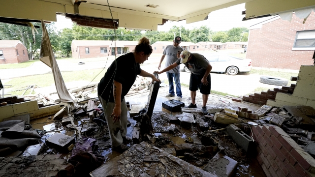 People look through a home damaged by a flood