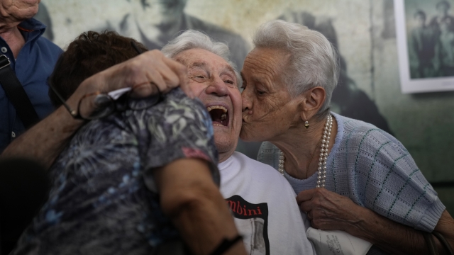 Martin Adler, a 97-year-old retired American soldier, embraces two Italians whom he saved as children during WWII.